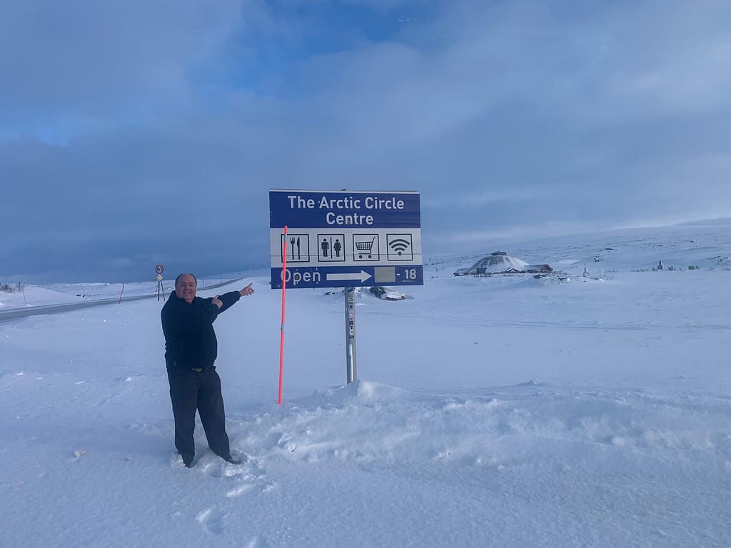 Paul Mason pointing to the Arctic Circle Centre sign